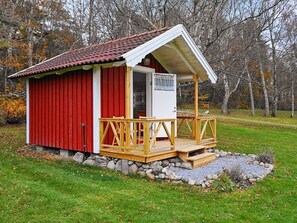 A small red and white building with a wooden deck and a stone foundation. - 6 Person Holiday Home in Askeron (Hjaelteby)
