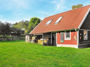 Kaksikerroksinen talo, jossa on punatiilinen katto, katettu kuisti ja kivimuuri.