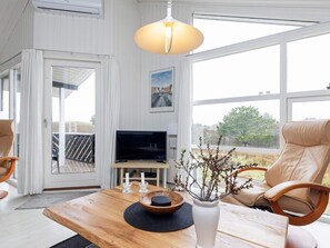 A modern living room with a wooden coffee table, a television, and a large window offering a view of the outdoors. - 4 Star Holiday Home in Blokhus (Blokhus)