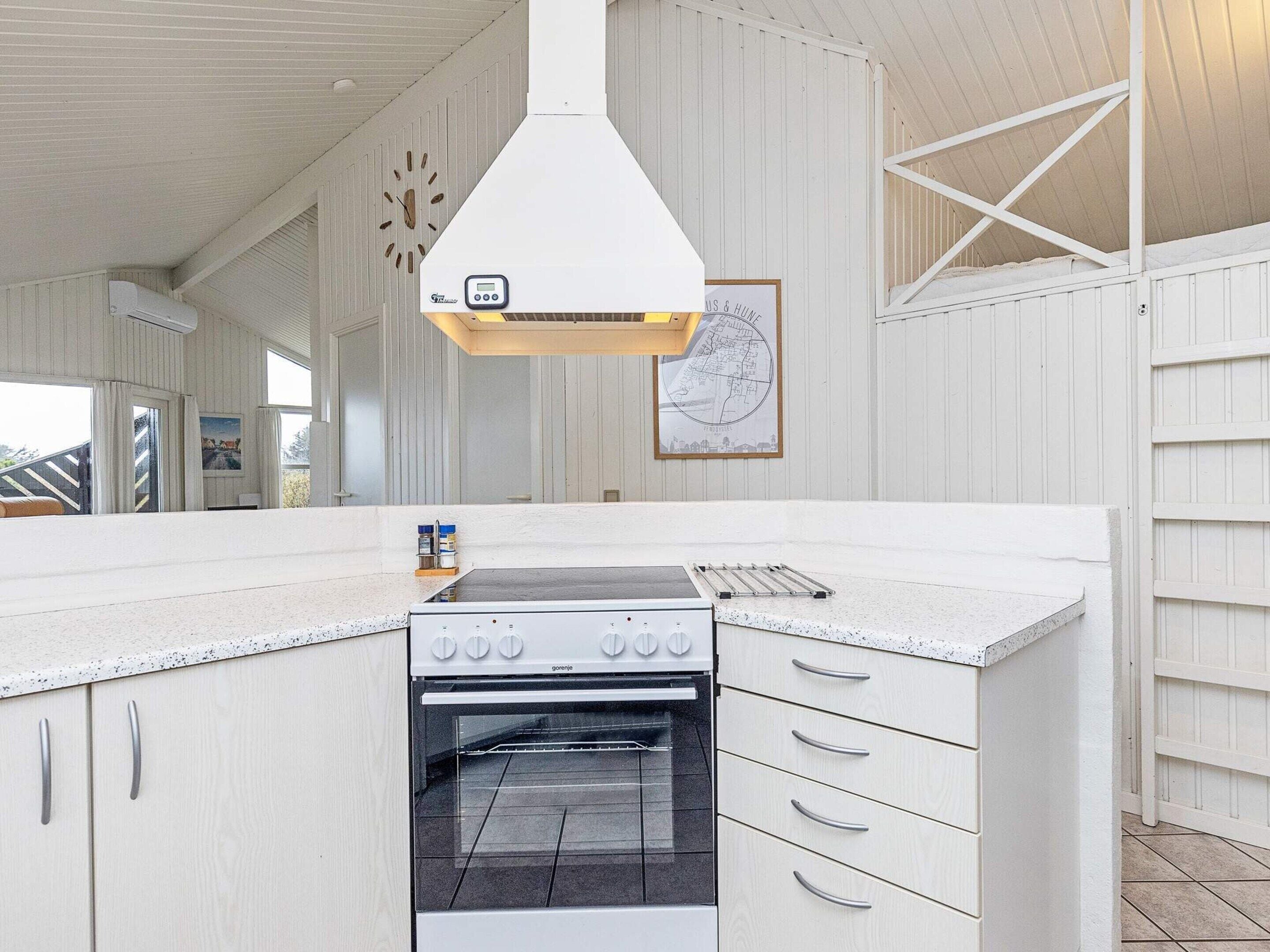 A kitchen with a built-in oven, a clock, and a map on the wall.
