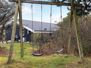 Un portique en bois dans une cour, avec une maison en arrière-plan.