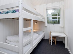 Habitación con literas, un escritorio, una silla, una ventana con vista a la vegetación y una lámpara en el techo.