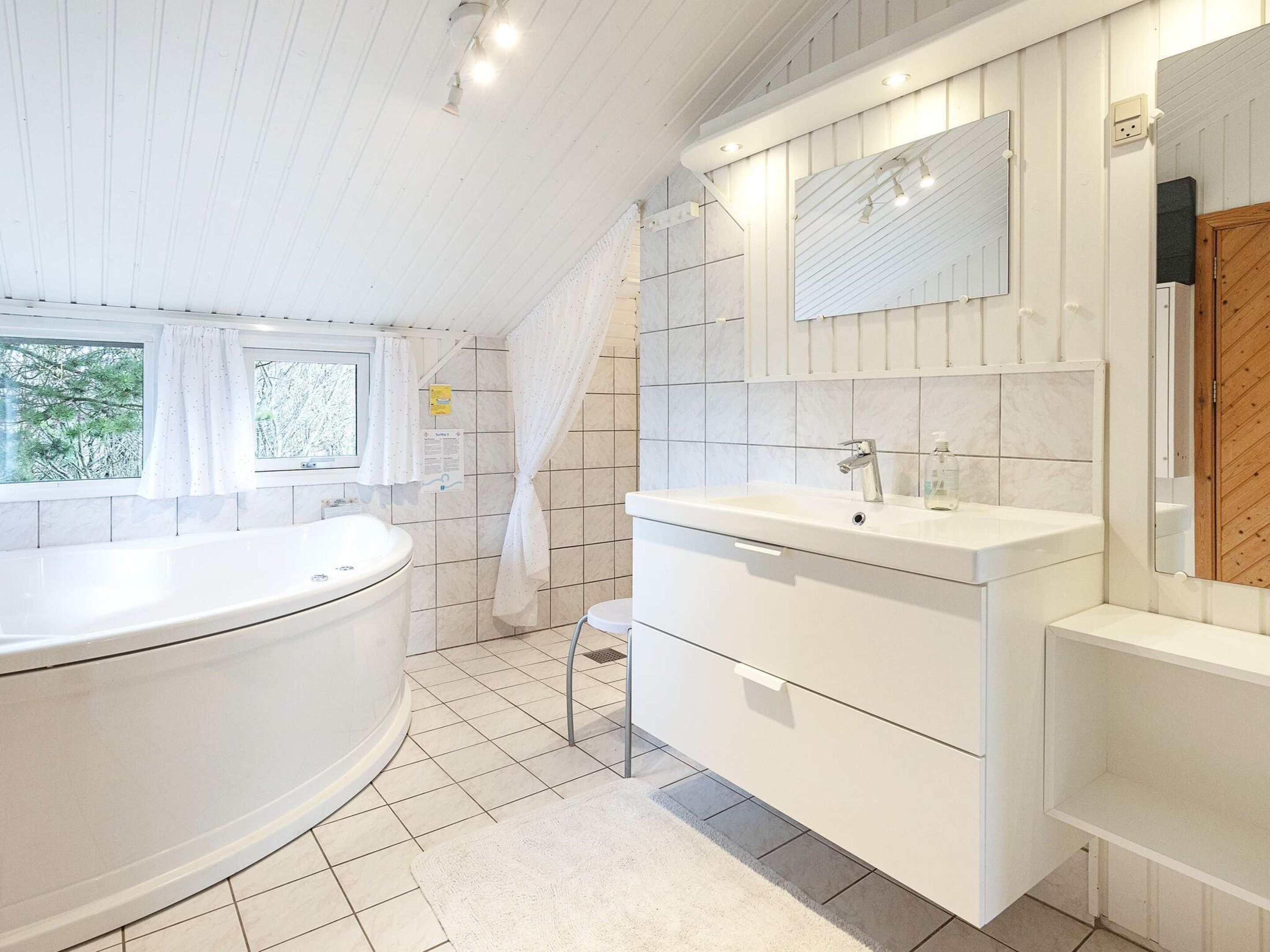 Un bagno moderno con una vasca da bagno indipendente, un mobile lavabo con specchio e uno spazio doccia.