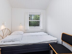 A bedroom with a bed, a window, a bedside lamp, and a chair. - 4 Star Holiday Home in Blokhus (Blokhus)
