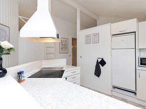 A kitchen with white cabinetry, a built-in oven, and a stainless steel refrigerator.