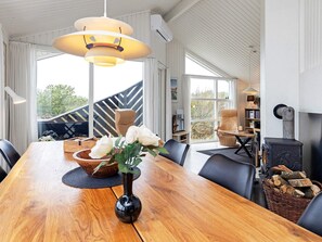 Un coin repas avec une table en bois, des chaises, un vase de fleurs et un luminaire suspendu moderne.
