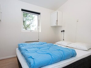 Un dormitorio con una cama individual, una ventana, un radiador y un mueble fijado a la pared.