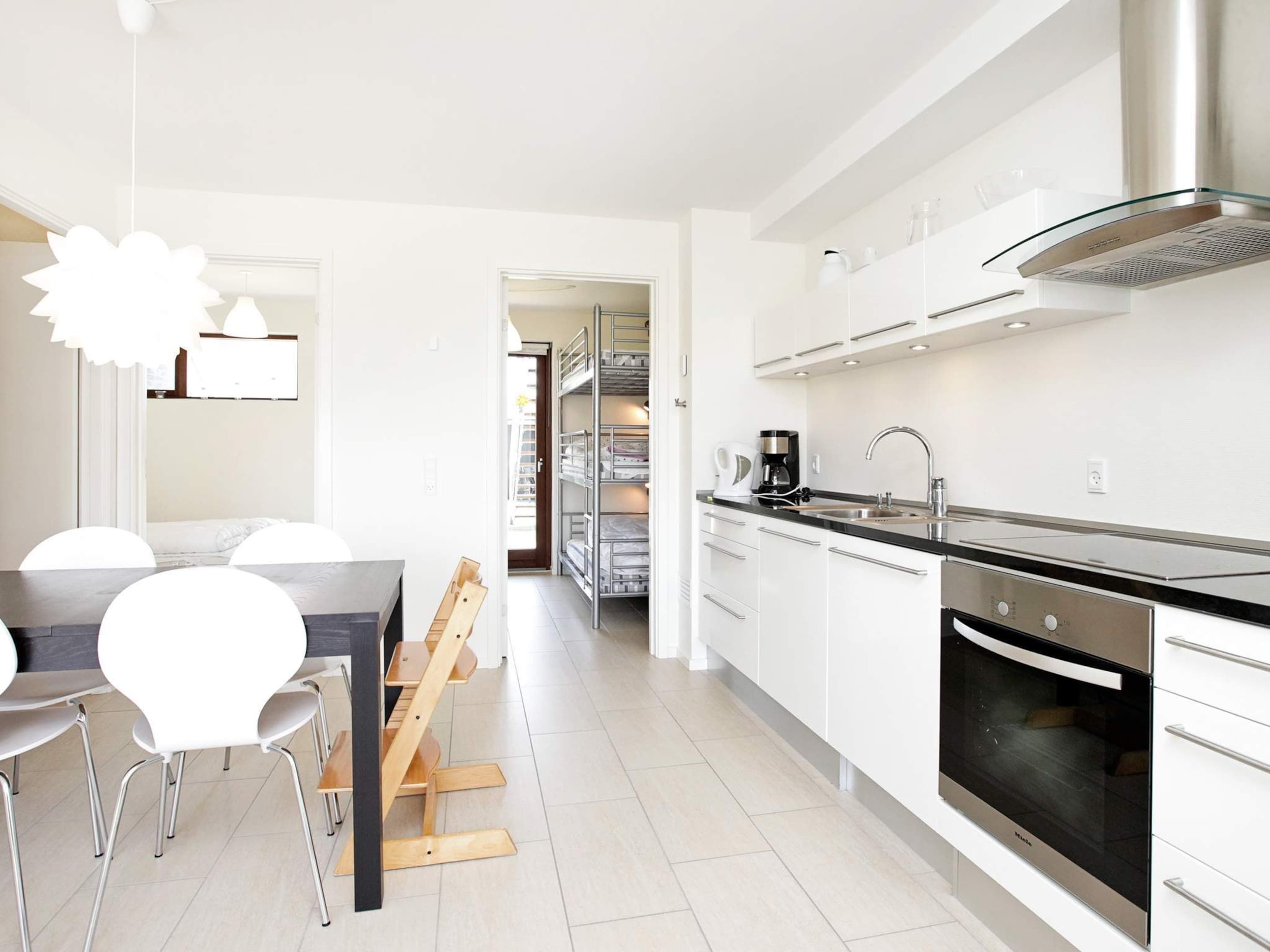 A modern kitchen with a built-in oven, stainless steel appliances, and a dining area with a table and chairs.