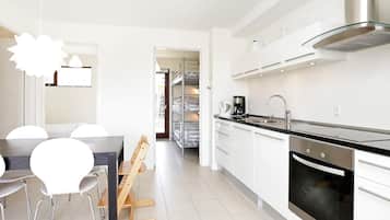 A modern kitchen with a built-in oven, stainless steel appliances, and a dining area with a table and chairs.