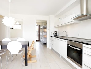 Una cocina moderna con horno integrado, electrodomésticos de acero inoxidable y un comedor con mesa y sillas.