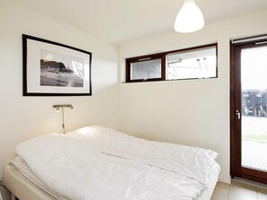 A bedroom with a bed, a framed picture, a window, and a door.
