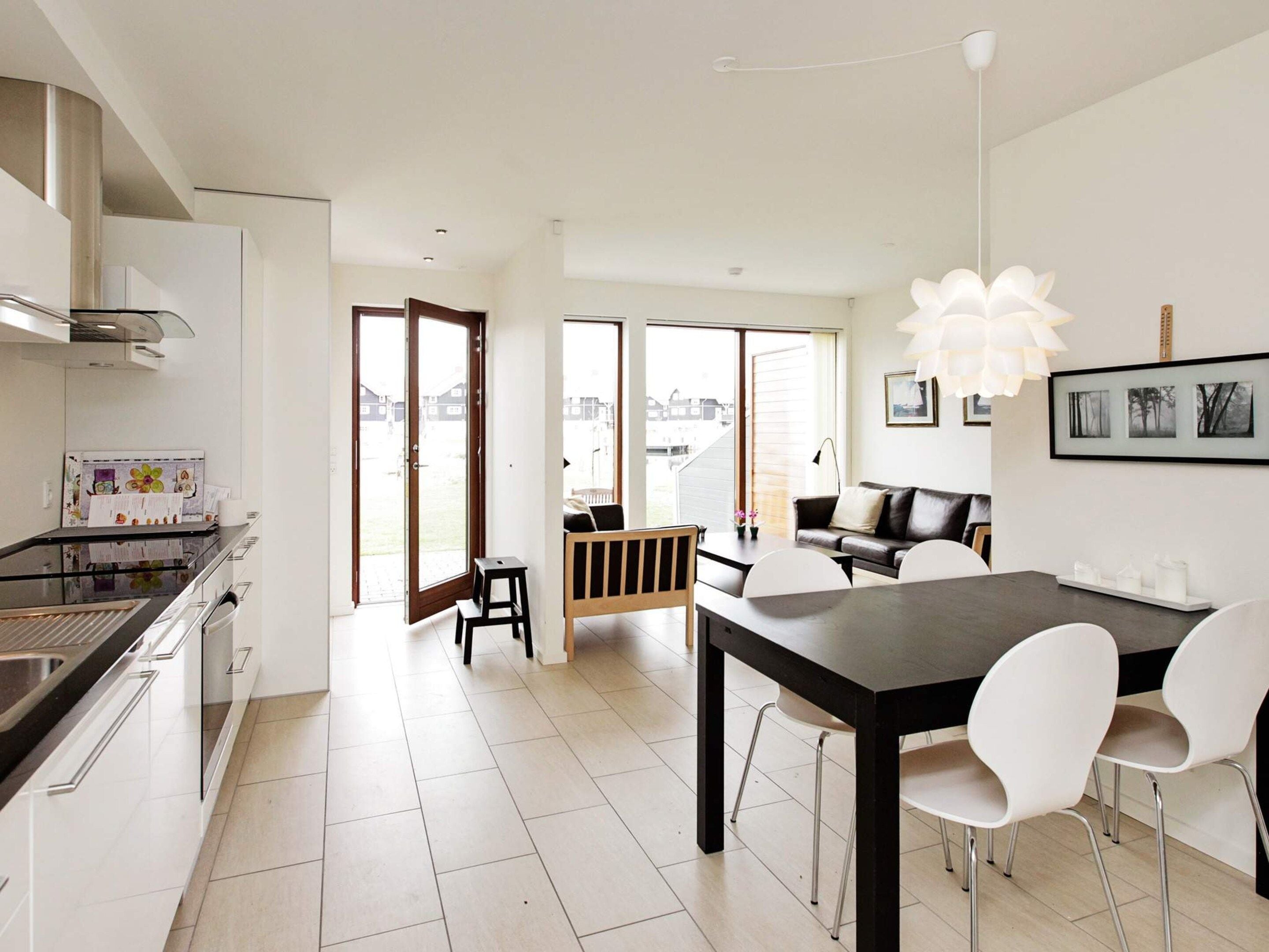 A modern kitchen with a dining area, large windows, and a view of the neighborhood.