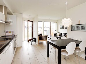 A modern kitchen with a dining area, large windows, and a view of the neighborhood.