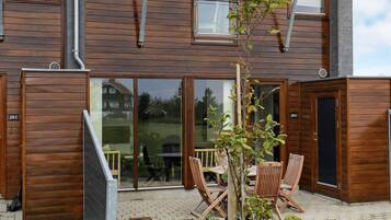 A wooden building with a glass door entrance, numbered 28C, and a small patio area with outdoor furniture.