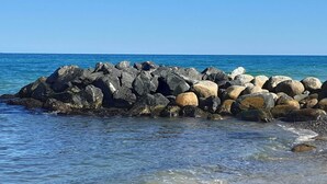Un littoral rocheux bordé d’une eau d’un bleu limpide et d’une mer calme.