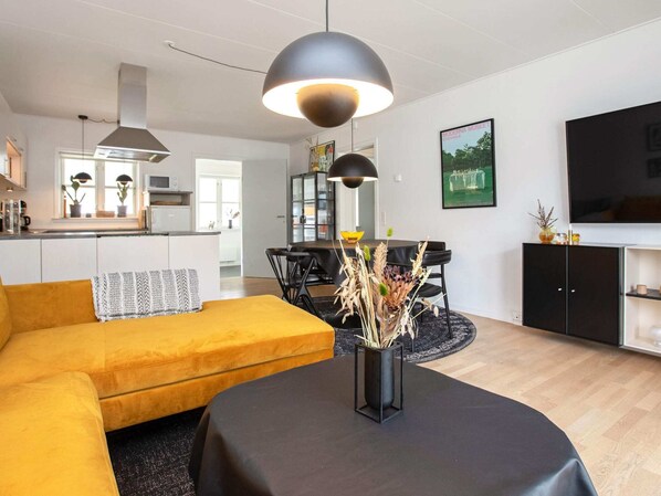 Een moderne woonkamer met een bank, eettafel en televisie.