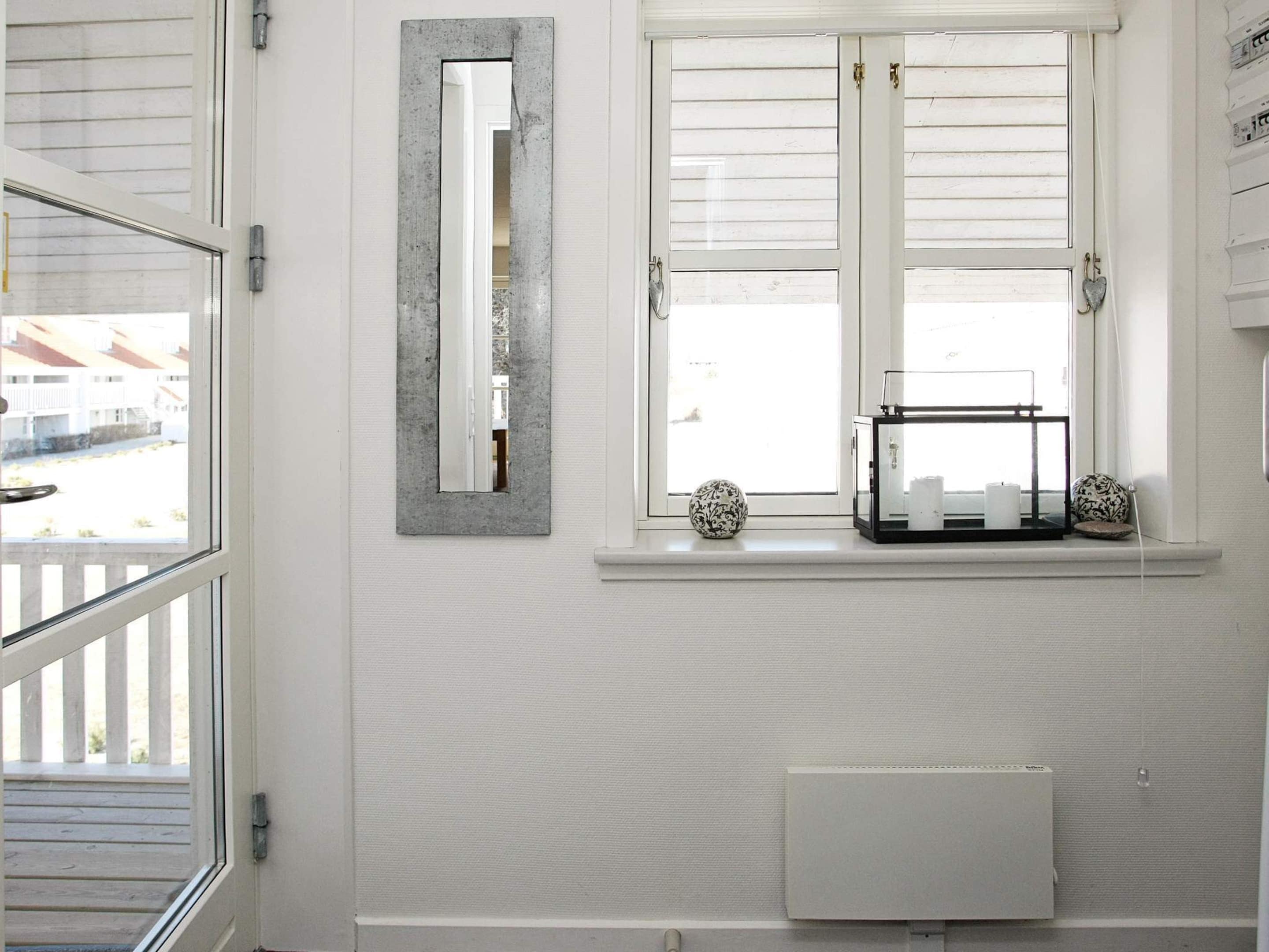 Un baño con ventana, un radiador y un estante con adornos.