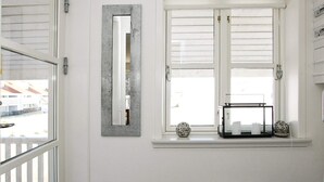 Une salle de bain avec une fenêtre, un radiateur et une étagère ornée d’objets décoratifs.