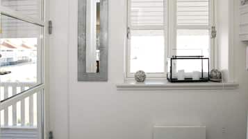 Un baño con ventana, un radiador y un estante con adornos.