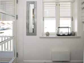 Une salle de bain avec une fenêtre, un radiateur et une étagère ornée d’objets décoratifs.