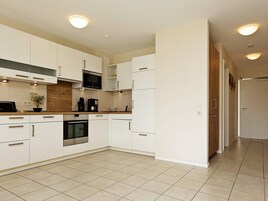 A modern kitchen with white cabinetry, a microwave, an oven, and a coffee maker.