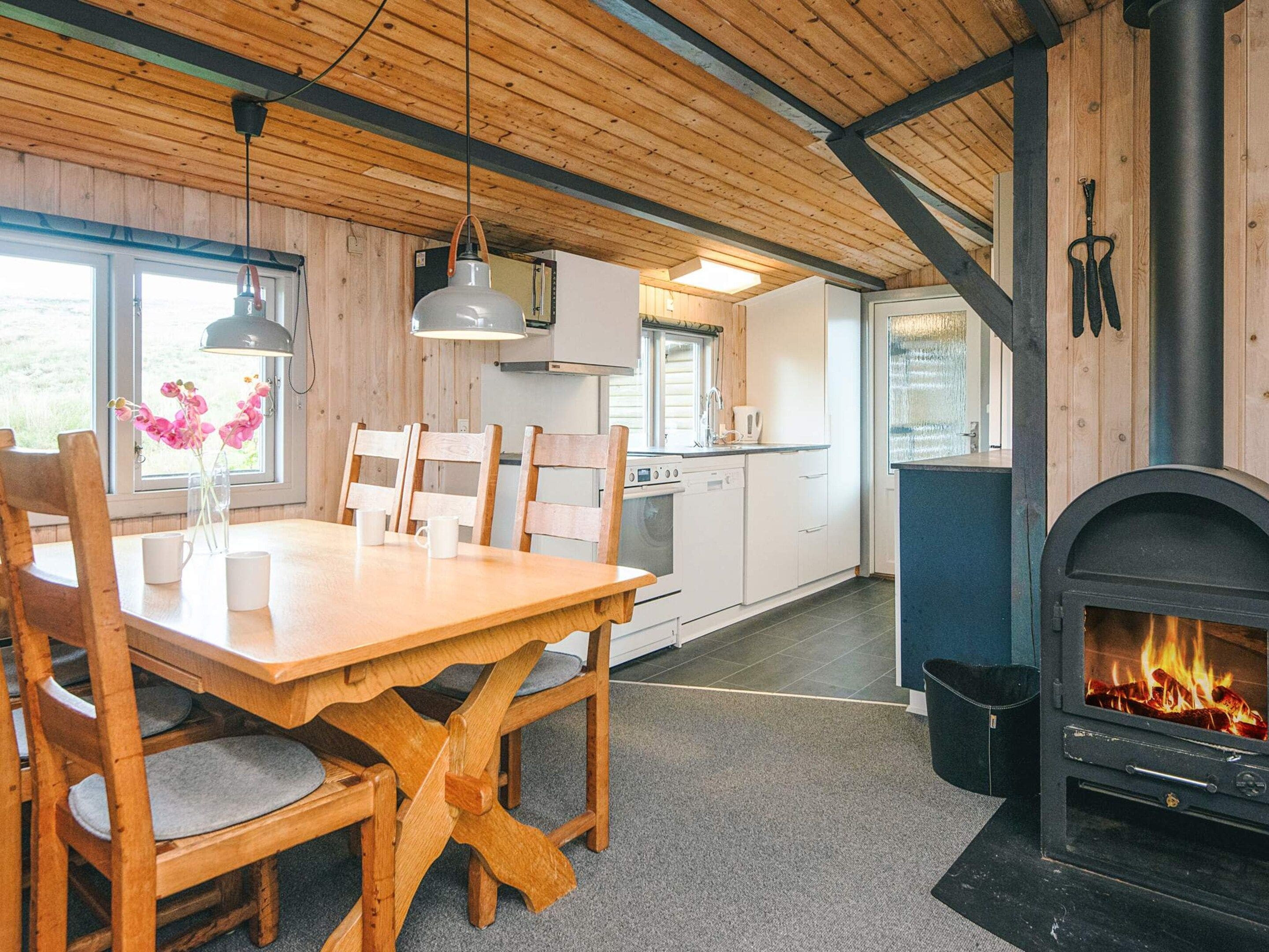 Ein gemütliches Blockhaus-Interieur mit Essbereich, Küche und Kamin.