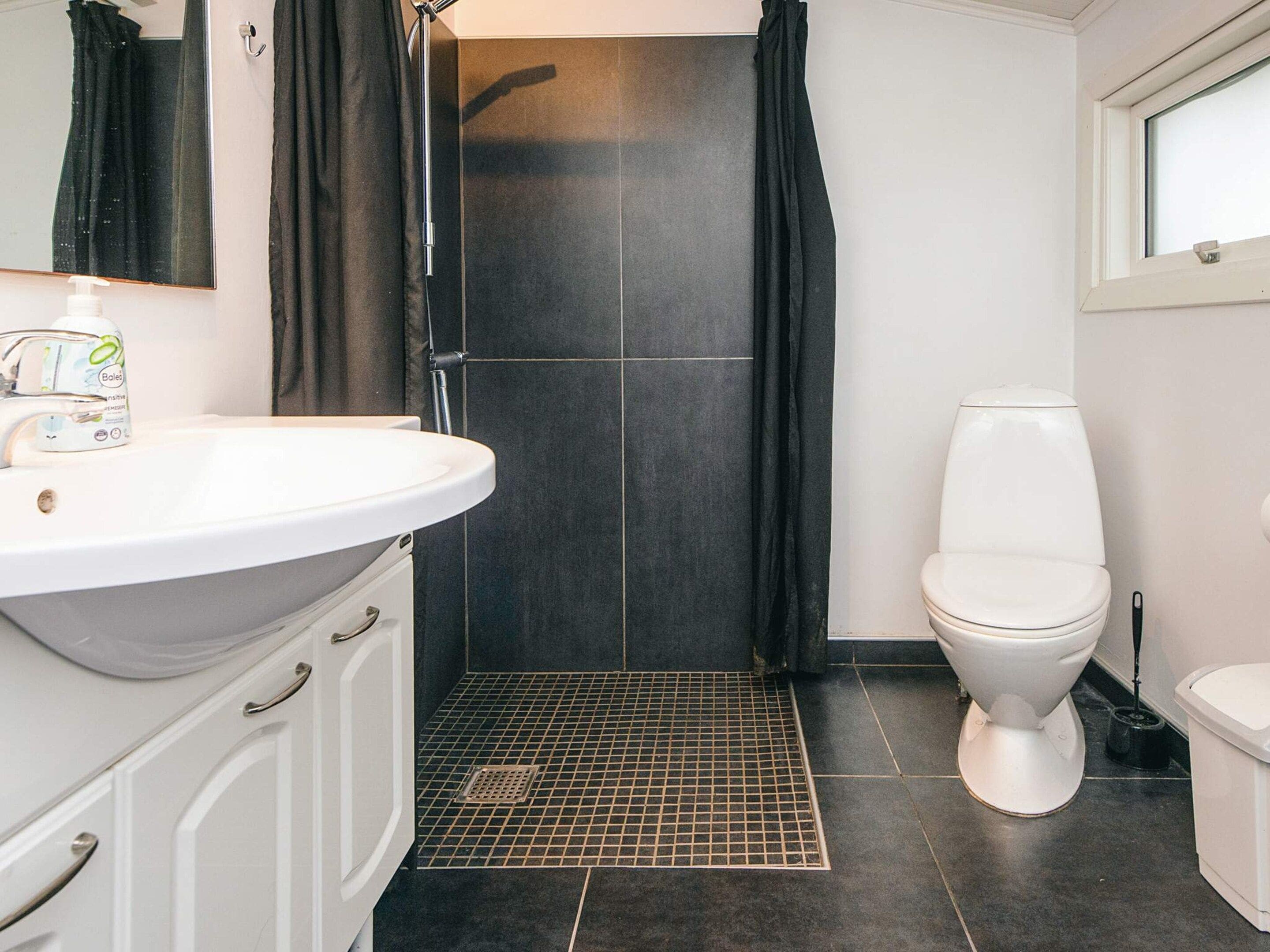 A bathroom with a white sink, a toilet, and a shower area.