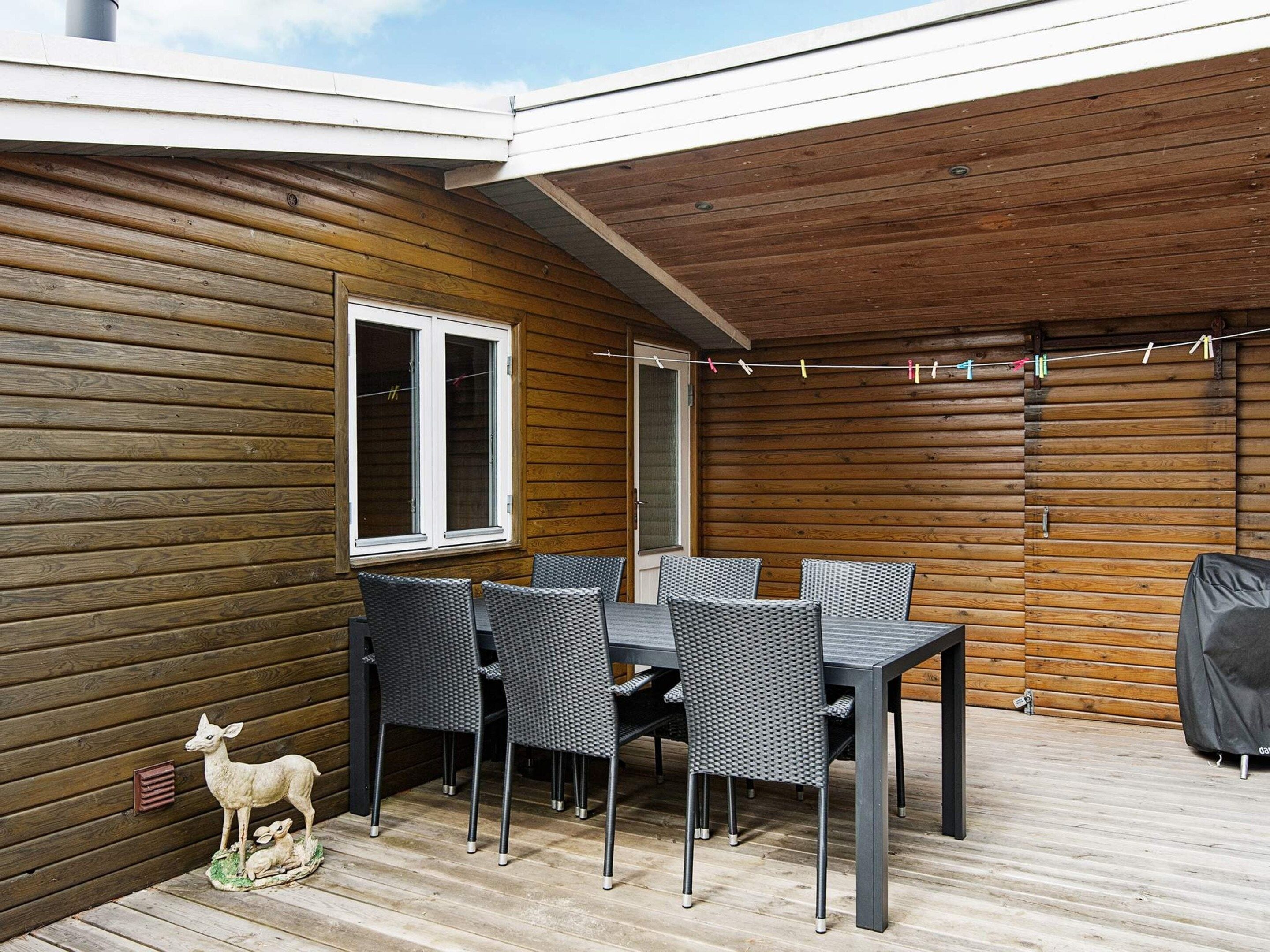 A covered patio area with a table and chairs, a window, and a decorative deer sculpture.