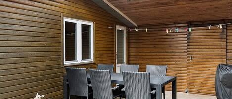 A covered patio area with a table and chairs, a window, and a decorative deer sculpture.
