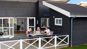A modern house with a deck, a sliding glass door, and a small outdoor table. - 4 Person Holiday Home in Gudhjem (Gudhjem)