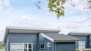 A two-story residential building with a covered porch and a garage. - 4 Person Holiday Home in Gudhjem (Gudhjem)