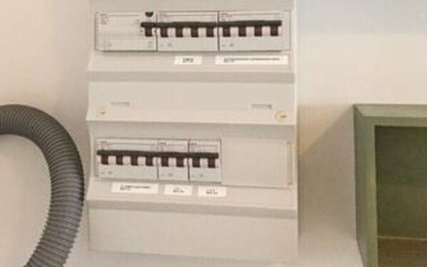 A utility panel with multiple circuit breakers and a flexible conduit.