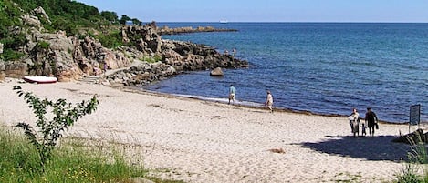 Een strand met rotsachtige kliffen, een zandstrand en een rustige zee.