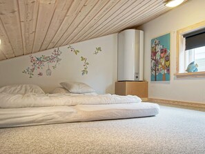 A bedroom with a bed, a wall-mounted air conditioner, and a window with a view.