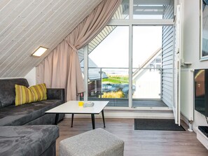 A modern loft bedroom with a large skylight, a sofa, a table, and a television.