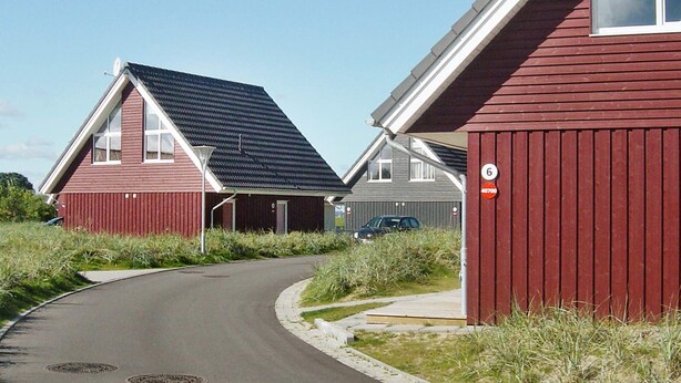 A residential area with red houses, a curved road, and a clear sky.