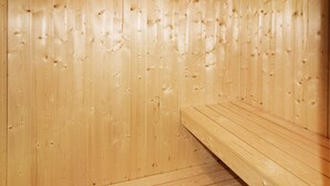 A wooden sauna with benches and a sloped floor.