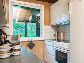 Une cuisine moderne avec une fenêtre, des meubles blancs, une cuisinière et une bouilloire.