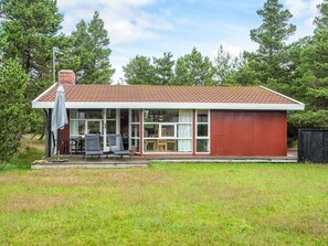 A single-story house with a red exterior and a covered patio area.