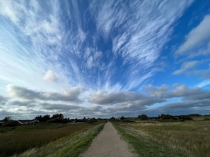 Un chemin de gravier traverse un champ d’herbe, sous un ciel dégagé.