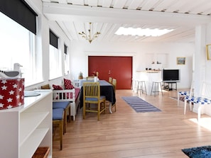 Un salon moderne comprenant un coin repas, une porte rouge, un téléviseur et une fenêtre donnant sur un beau paysage.