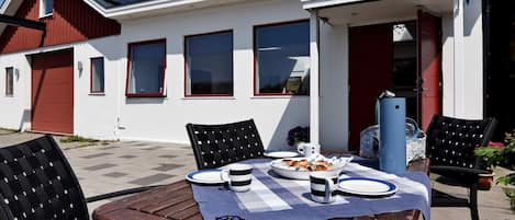 Un área de comedor al aire libre con una mesa preparada para dos, sillas y una bandera.