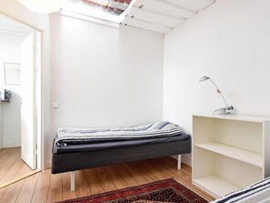 Una camera minimalista con un letto, una scrivania e uno scaffale.
