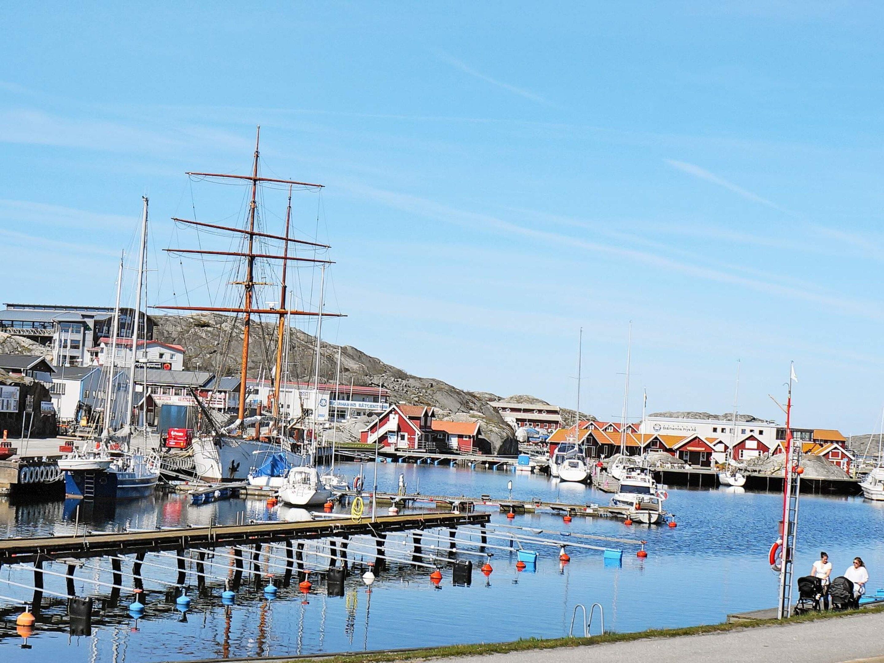 A harbor with various boats, including a tall ship, docked alongside buildings with red roofs.