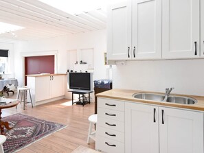 Une cuisine moderne avec des meubles blancs, un plan de travail en bois et un téléviseur encastré.