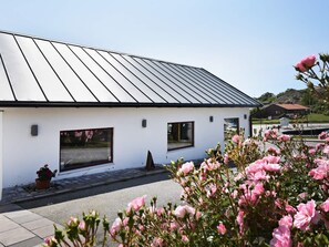 A modern building with a metal roof, large windows, and a paved entrance. - Holiday Home in Skærhamn (Skaerhamn)
