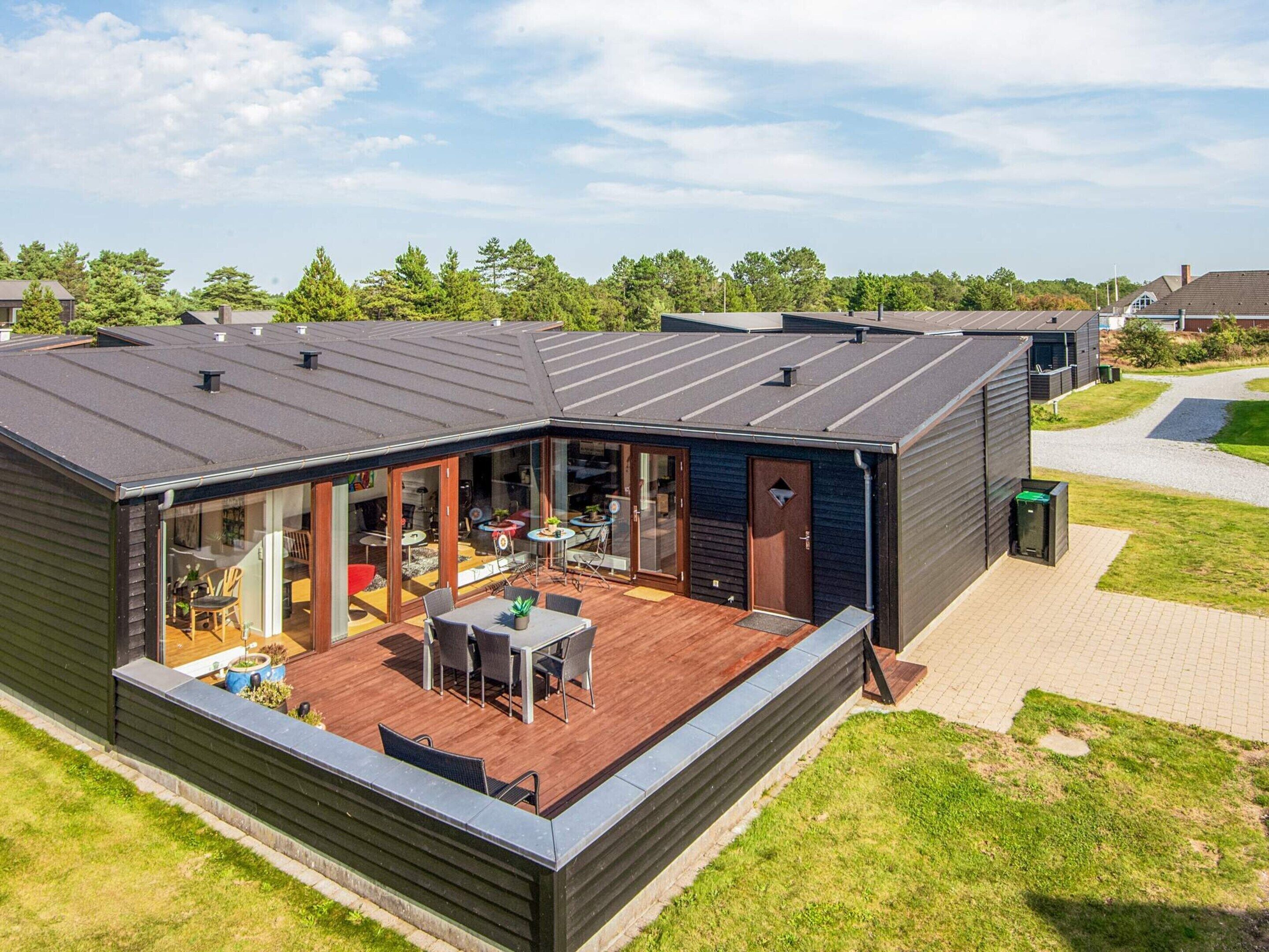 A modern, single-story building with a covered patio area featuring a dining table and chairs.