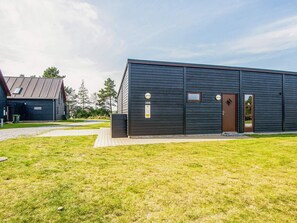 Ein modernes Gebäude mit dunkler Fassade, einer nummerierten Tür und einem kleinen Fenster.