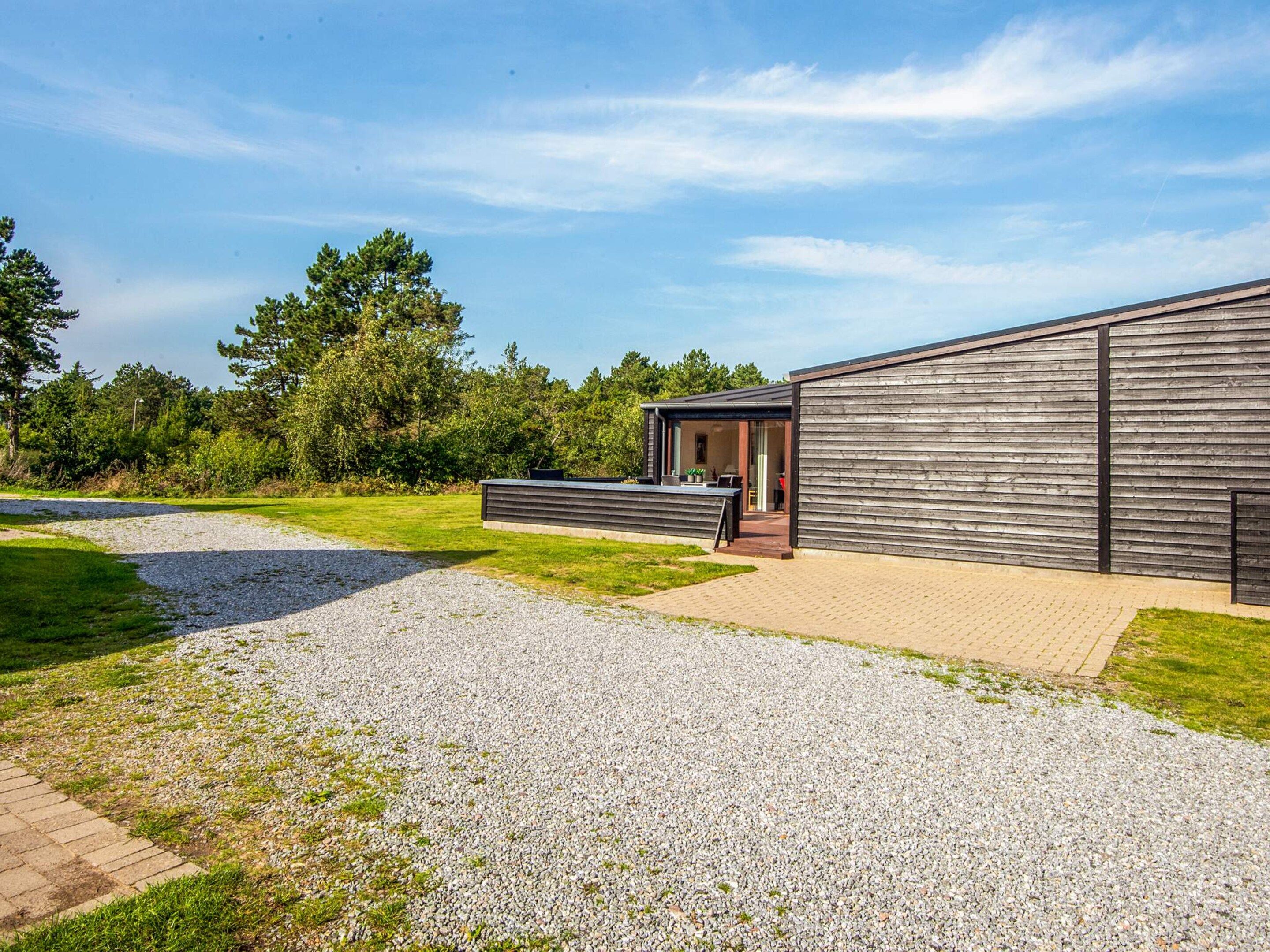 A modern building with a gravel driveway leading to a covered outdoor area.