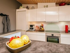 A modern kitchen with white cabinets, a built-in oven, and a coffee maker on the counter.
